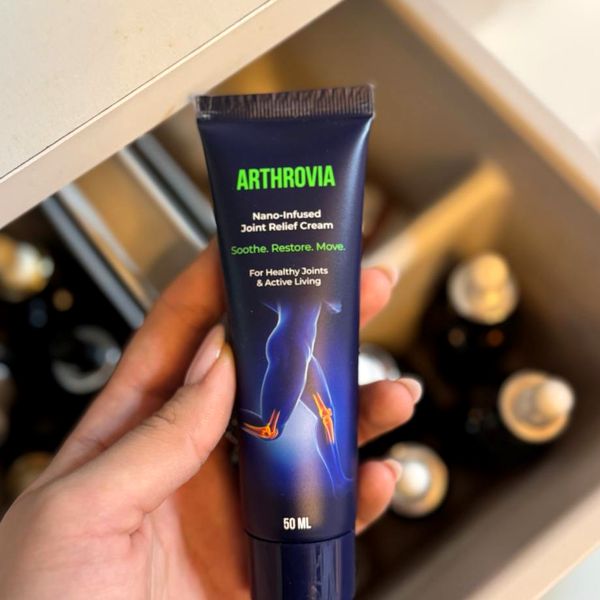 Tmavomodrá tuba Arthrovia so zeleným nápisom a údajom 50 ml v ženskej ruke nad otvorenou zásuvkou s kozmetikou