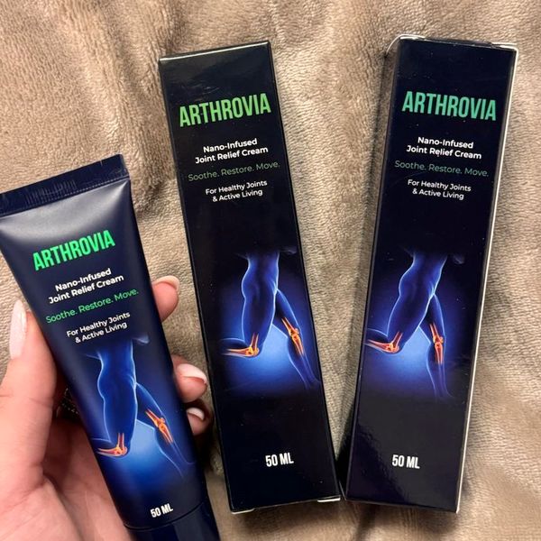 Ženská ruka drží tubu Arthrovia vedľa dvoch krabičiek s údajom 50 ml položených na hnedej huňatej deke