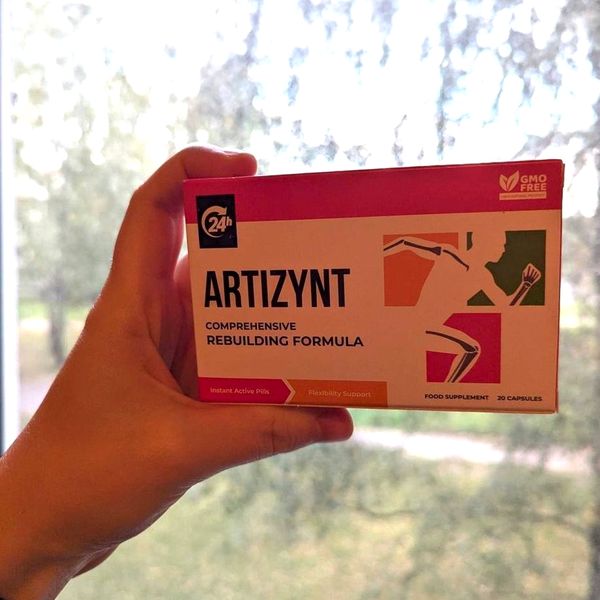 Ruka drží krabičku ArtiZynt pred oknom, za sklom vidno rozmazané stromy a trávnik