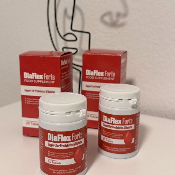Dve biele dózy DiaFlex Forte s červenou etiketou a údajom 20 tablets, za nimi dve červené krabičky na bielom stolíku