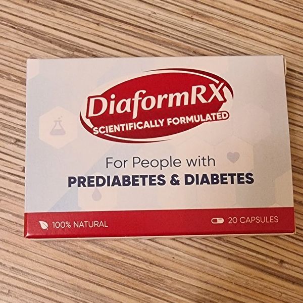 Plochá bielosivá krabička DiaformRX s červeným oválnym logom a červeným pásom s údajom 20 capsules, položená na pásikavej drevenej doske