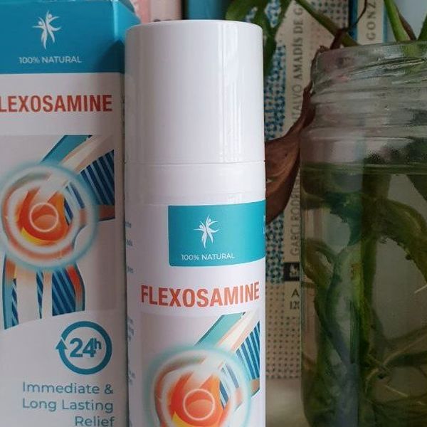 Detail bielej fľaštičky Flexosamine Gel s nasadeným uzáverom pri krabičke, vedľa sklenený pohár so stonkami rastliny vo vode