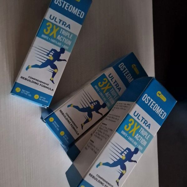 Tri modro-biele krabičky Osteomed s bežiacou postavou položené cez seba na bielom podklade v tlmenom svetle