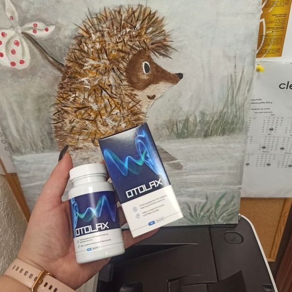Ruka drží dózu a krabičku Otolax pred maľovaným obrázkom ježka, pod ním je čierna tlačiareň